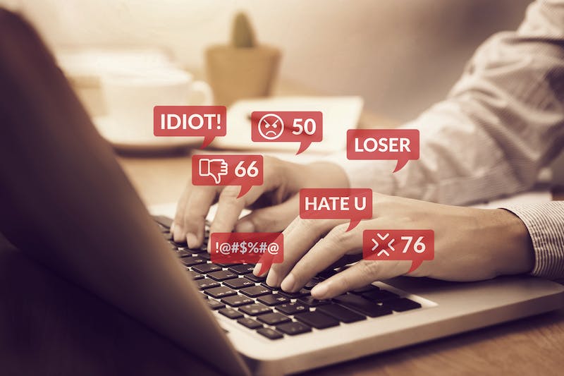 deleting negative comments on social media - cyber bullying concept. people using notebook computer laptop for social media interactions with notification icons of hate speech and mean comment in social network