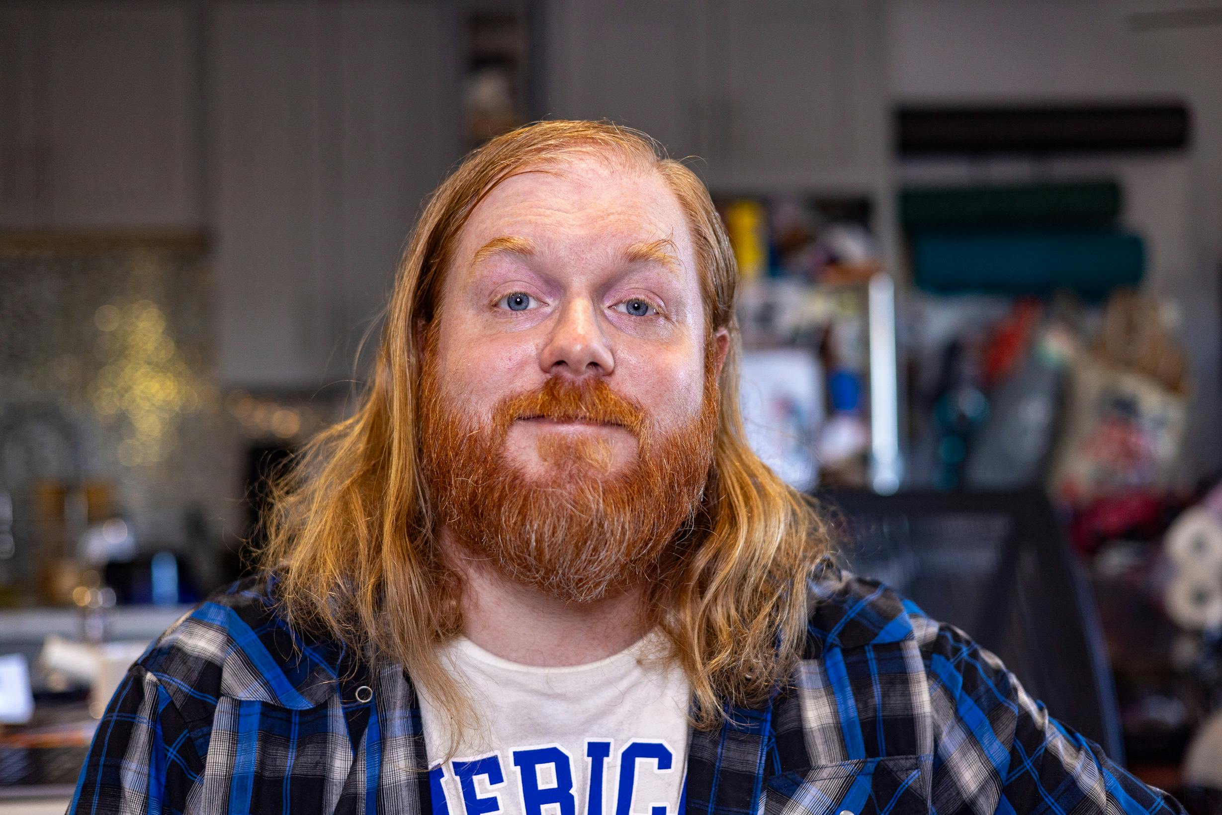 self portrait of a bearded red headed man with long hair and a blue shirt