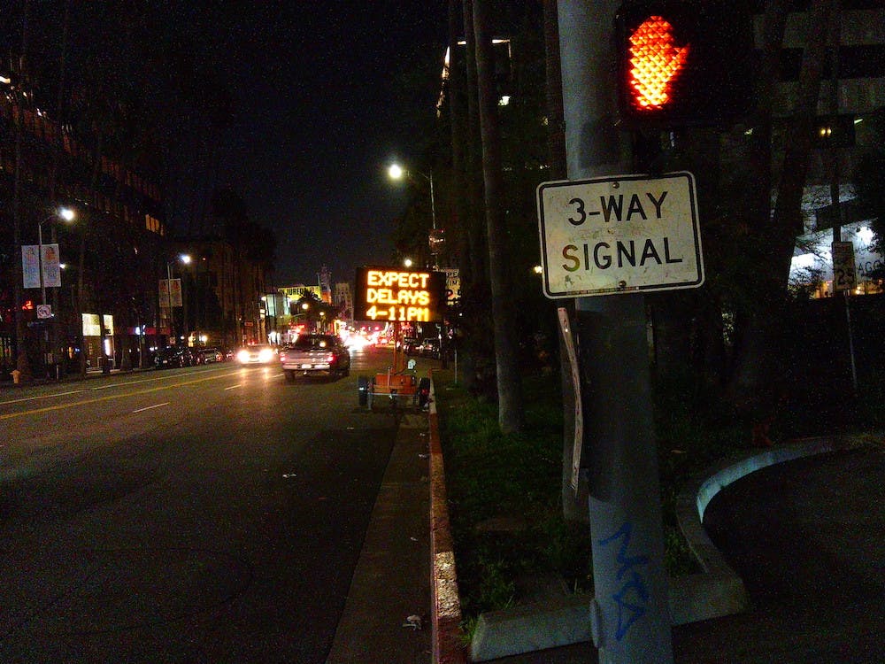street sign in low light, no flash, saying expect delays