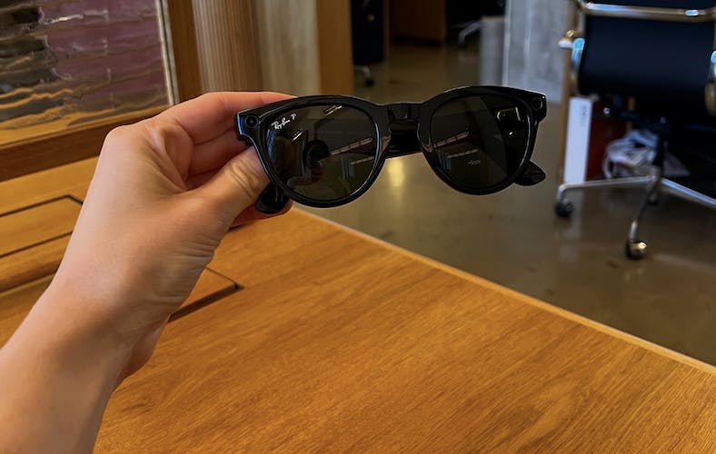 Someone holding up rayban meta smart glasses with their hand