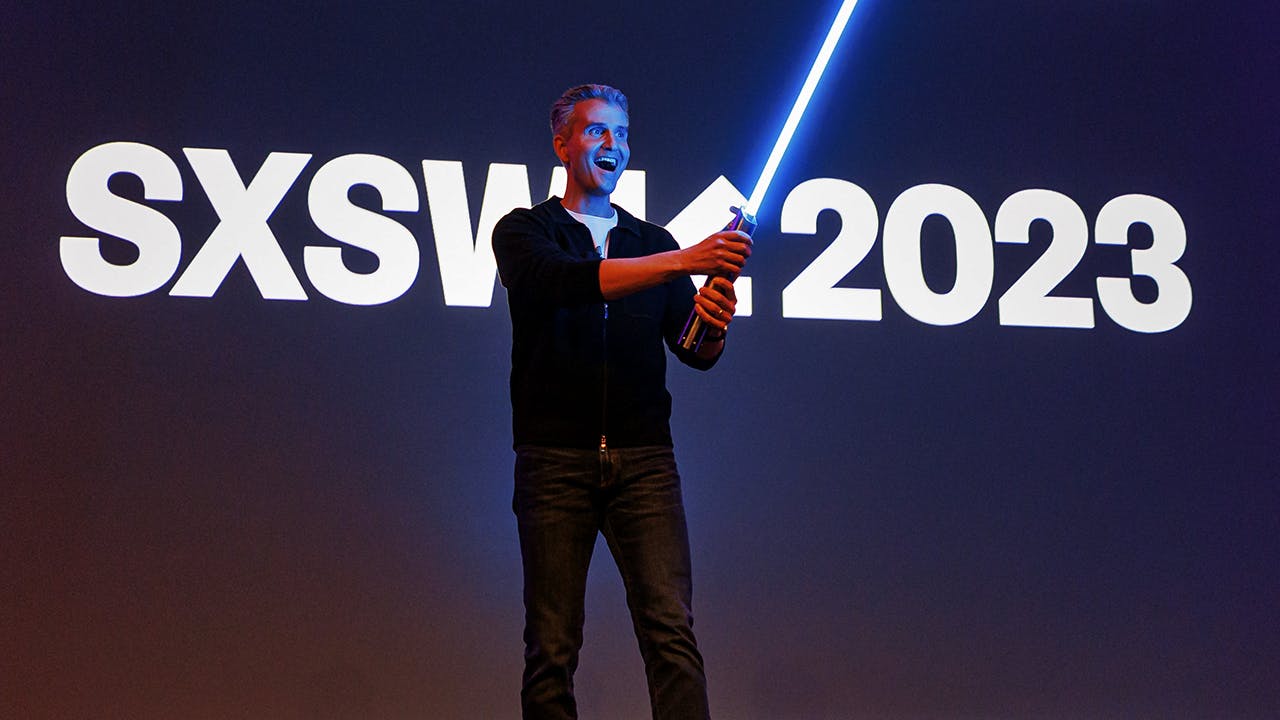 What is SXSW - Andy Wenstrand holding a light saber and speaking at the Creating Happiness The Ar and Science of Disney Parks Storytelling